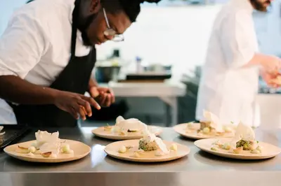 a chef preparing food on plates in a kitchen at Tanda Tula Safari Camp in Timbavati Game Reserve