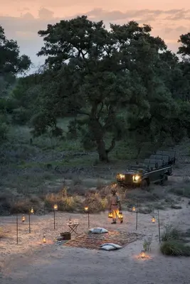 a man sitting in front of a car with lights at Tanda Tula Safari Camp in Timbavati Game Reserve