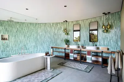 a bathroom with two sinks and a tub and mirrors at Tanda Tula Safari Camp in Timbavati Game Reserve