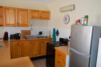 a kitchen with a white refrigerator and wooden cabinets at Holiday Flat Stormvoel 547 in Hazyview