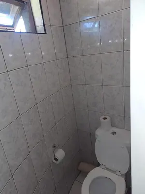 a white bathroom with a toilet and a window at Horizon View Chalets in Graskop