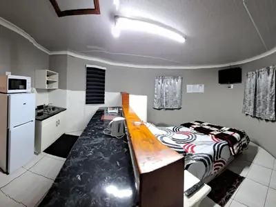 a small room with a bed and a kitchen at Horizon View Chalets in Graskop