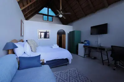 a bedroom with a bed and a desk and a couch at Bali at Scenic Haven Lodge in Hartbeespoort in Hartbeespoort