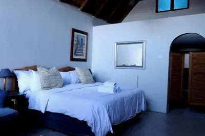 a bedroom with a large bed with white sheets at Bali at Scenic Haven Lodge in Hartbeespoort in Hartbeespoort