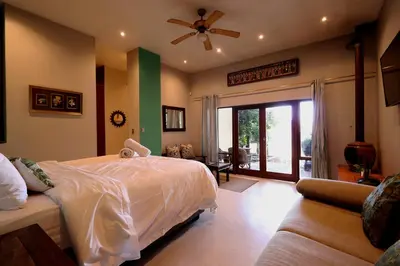 a bedroom with a large bed and a couch at Bali at Scenic Haven Lodge in Hartbeespoort in Hartbeespoort