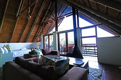 a living room with two couches and a large window at Bali at Scenic Haven Lodge in Hartbeespoort in Hartbeespoort