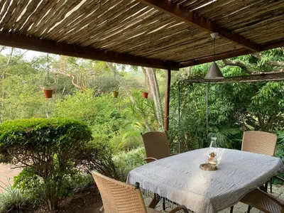 a white table and chairs under a wooden pergola at Nightjar Guest Lodge in Nelspruit