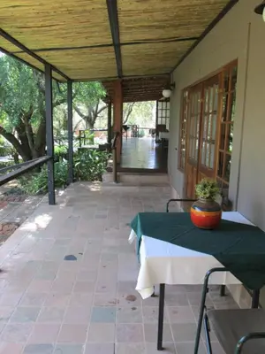 a patio with a table with a vase on it at Tuskers Bush Lodge B&B in Hartbeespoort