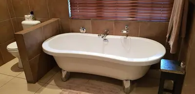 a white bath tub in a bathroom with a toilet at Tuskers Bush Lodge B&B in Hartbeespoort