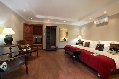 a bedroom with a large bed with a red blanket at Tuskers Bush Lodge B&B in Hartbeespoort