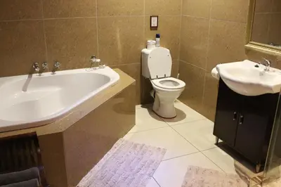 a bathroom with a tub and a toilet and a sink at Tuskers Bush Lodge B&B in Hartbeespoort