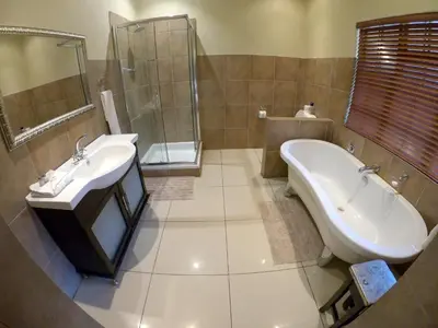 a bathroom with a tub and a sink and a bath tub at Tuskers Bush Lodge B&B in Hartbeespoort
