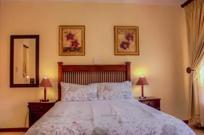a bedroom with a bed with two lamps and a mirror at Marlot Guest House in Polokwane