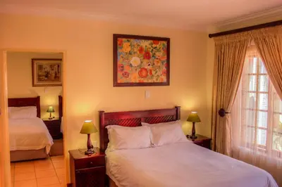 a bedroom with two beds and a painting on the wall at Marlot Guest House in Polokwane