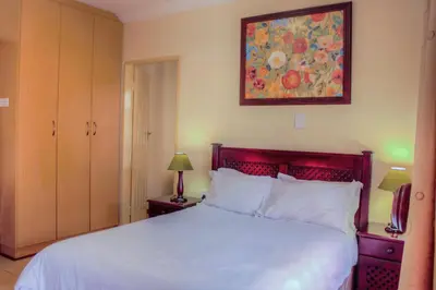 a bedroom with a white bed and a painting on the wall at Marlot Guest House in Polokwane