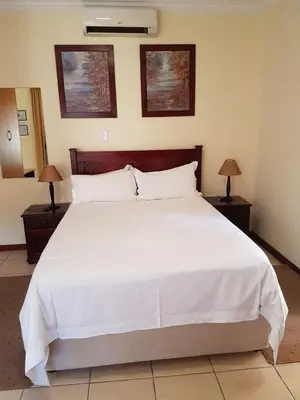 a bedroom with a large white bed with two lamps at Marlot Guest House in Polokwane