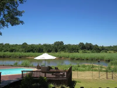a patio with an umbrella next to a pool at Sabie River Bush Lodge in Hazyview