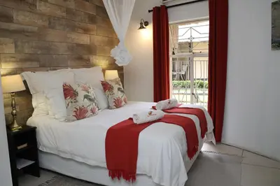 a bedroom with a bed with a red and white blanket at Sabie River Bush Lodge in Hazyview