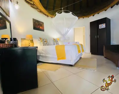 a bedroom with a bed with yellow and white sheets at Sabie River Bush Lodge in Hazyview