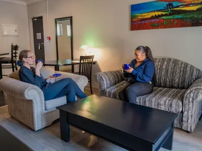 two people sitting on couches in a living room with their cell phones at ANEW Hotel Witbank Emalahleni in Witbank