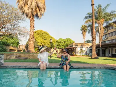 a man and two women sitting next to a swimming pool at ANEW Hotel Witbank Emalahleni in Witbank