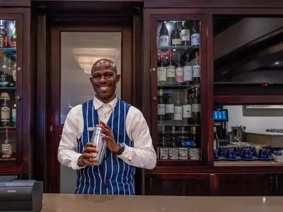 a man standing behind a bar holding a drink at ANEW Hotel Witbank Emalahleni in Witbank