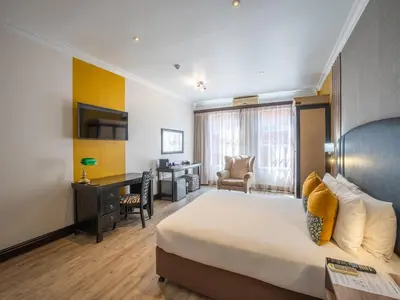 a hotel room with a bed and a desk and a bedroom at ANEW Hotel Highveld Emalahleni in Witbank