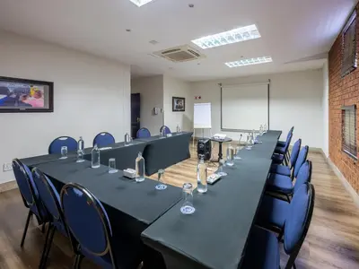 a meeting room with long tables and blue chairs at ANEW Hotel Highveld Emalahleni in Witbank