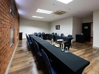 a conference room with tables and chairs and a brick wall at ANEW Hotel Highveld Emalahleni in Witbank