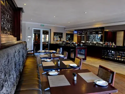 a restaurant with tables and chairs and a bar at ANEW Hotel Highveld Emalahleni in Witbank