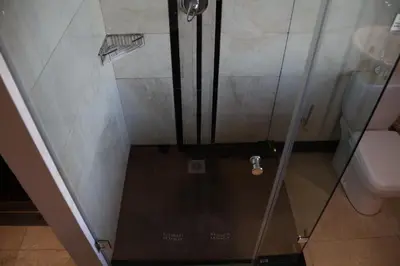 a shower with a glass door next to a toilet at Kosmos Lodge in Hartbeespoort