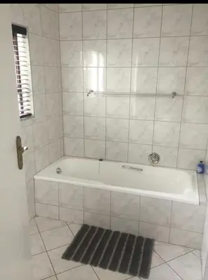 a white bath tub in a bathroom with a rug at Kosmos Lodge in Hartbeespoort