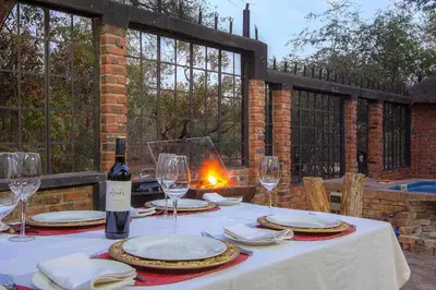 a table with a bottle of wine and glasses on it at Wildgoose Lodge in Marloth Park