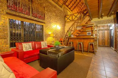 a living room with a red couch and a table at Wildgoose Lodge in Marloth Park