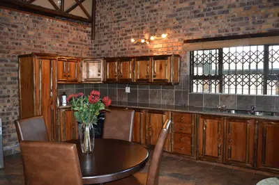 a kitchen with a table with a vase of flowers on it at Wildgoose Lodge in Marloth Park