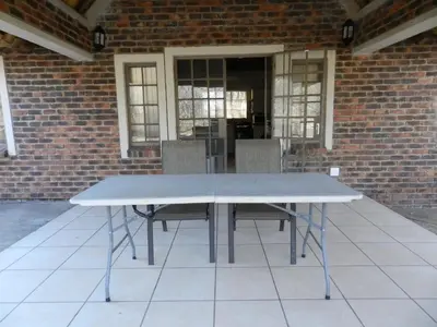 a white table with chairs in front of a brick building at Impalas Walk in Marloth Park