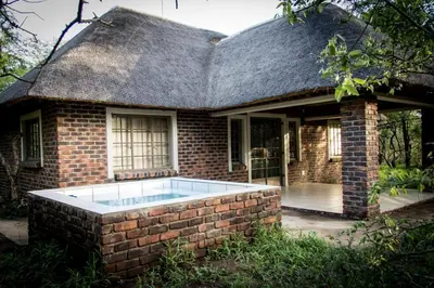 a brick house with a swimming pool in front of it at Impalas Walk in Marloth Park