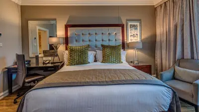 a bedroom with a bed and a desk and a chair at InterContinental Johannesburg OR Tambo Airport Hotel by IHG in Kempton Park