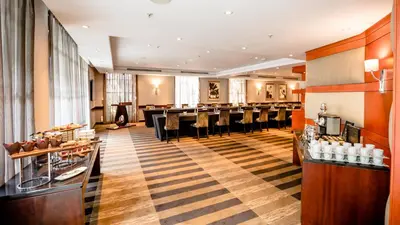 a restaurant with a long bar with black chairs at InterContinental Johannesburg OR Tambo Airport Hotel by IHG in Kempton Park