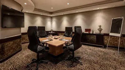 a conference room with a table and black chairs at InterContinental Johannesburg OR Tambo Airport Hotel by IHG in Kempton Park