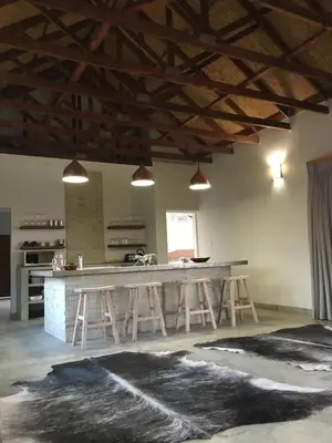 a kitchen with a large island in a room with beams at MANZINI RIVER HOUSE - Mjejane Private Game Reserve, Greater Kruger National Park in Hectorspruit