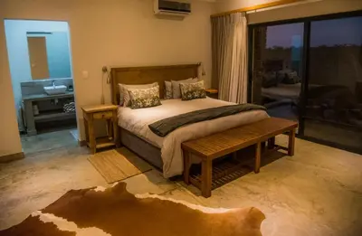 a bedroom with a large bed and a bathroom at MANZINI RIVER HOUSE - Mjejane Private Game Reserve, Greater Kruger National Park in Hectorspruit