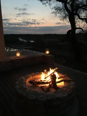 a fire pit with a person sitting around it at MANZINI RIVER HOUSE - Mjejane Private Game Reserve, Greater Kruger National Park in Hectorspruit
