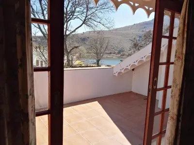 an open door to a balcony with a view at Nooitgedacht Trout Lodge in Lydenburg