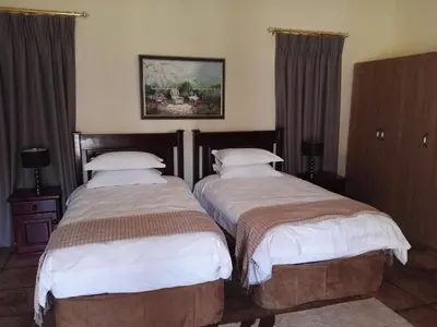 two beds in a hotel room with curtains at Nooitgedacht Trout Lodge in Lydenburg