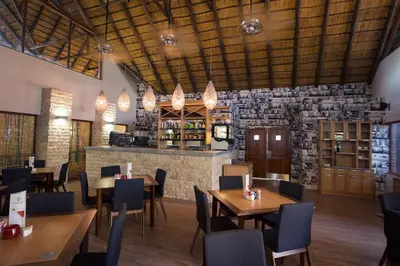a restaurant with wooden tables and chairs and a stone wall at Seasons Golf, Leisure, Spa in Hartbeespoort