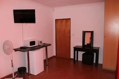 a room with a microwave and a table with a mirror at Bottom of Boden in Benoni