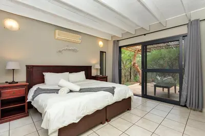 a bedroom with a bed and a sliding glass door at The Bush House in Hoedspruit