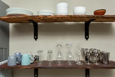 a shelf with glasses and plates and dishes on it at The Bush House in Hoedspruit