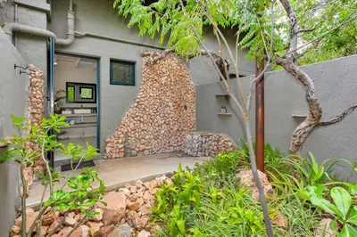 a building with a stone wall and a chair at The Bush House in Hoedspruit